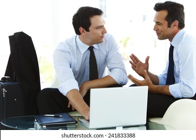 Businessmen Working Together On Laptop In Airport Lounge