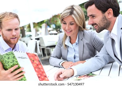 Businesspeople Deciding Menu At Sidewalk Cafe