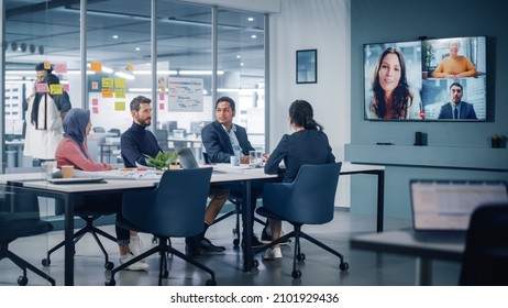 Businesspeople Do Video Conference Call With Big Wall TV In Office Meeting Room. Diverse Team Of Creative Entrepreneurs At Big Table Have Discussion. Specialists Work In Digital E-Commerce Startup