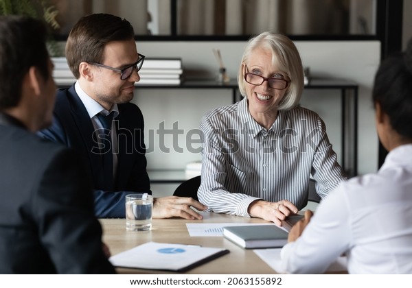 Businesspeople group of diverse gender\
generation hold negotiations at conference table. Business partners\
shareholders meet at boardroom discuss work on new project talk\
about profitable\
investments