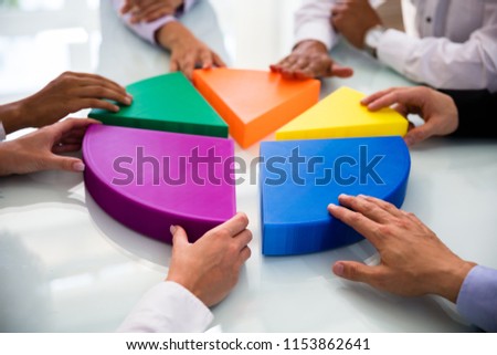 Businesspeople Hand Connecting Multi Colored Pieces Of Pie Chart On Desk