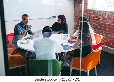 Businesspeople having a discussion in a meeting room. Experienced mature businessman briefing his colleagues during a meeting in a modern office. Group of businesspeople working as a team. - Powered by Shutterstock