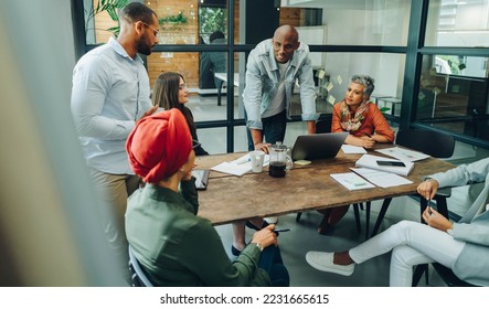 Businesspeople having a group discussion during a meeting in a creative office. Team of multicultural business professionals sharing ideas in an inclusive workplace. - Powered by Shutterstock