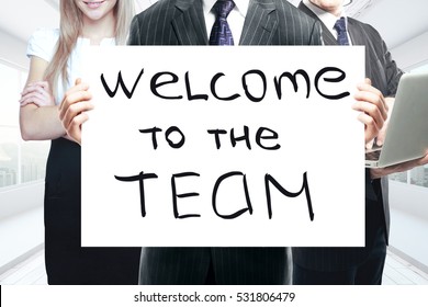 Businesspeople holding whiteboard with 'welcome to the team' text. Teamwork concept