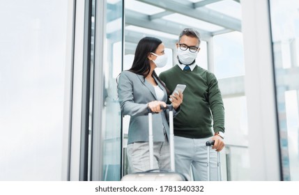 Businesspeople with luggage going on business trip, wearing face masks at the airport. - Powered by Shutterstock