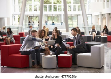 Businesspeople Meeting In Busy Lobby Of Modern Office