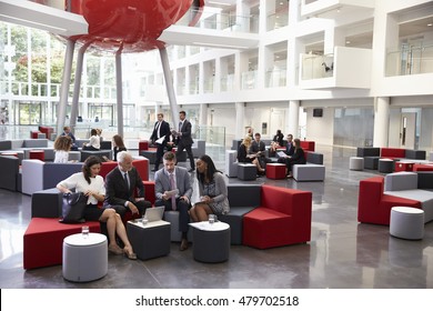 Businesspeople Meeting In Busy Lobby Of Modern Office