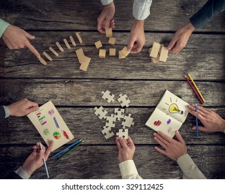 Businesspeople Organizing Business Strategy While Holding Puzzle Pieces, Writing Down Ideas On Paper And Rearranging Wooden Blocks. Concept Of Brainstorming, Management, Innovation Or Creativity. 