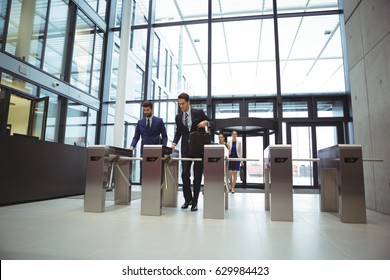 Businesspeople scanning their cards at turnstile gate in office - Powered by Shutterstock