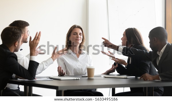 Businesspeople sit at desk, while stressed\
colleagues accusing screaming express negative emotion to young\
businesswoman she meditating looking serene and calm, no stress\
anxiety at workplace\
concept