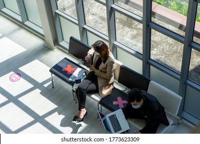 Businesspeople Sit In The Office Far Apart From Colleague In The Office To Prevent Virus Pandemic. Social Distancing New Normal Concept.