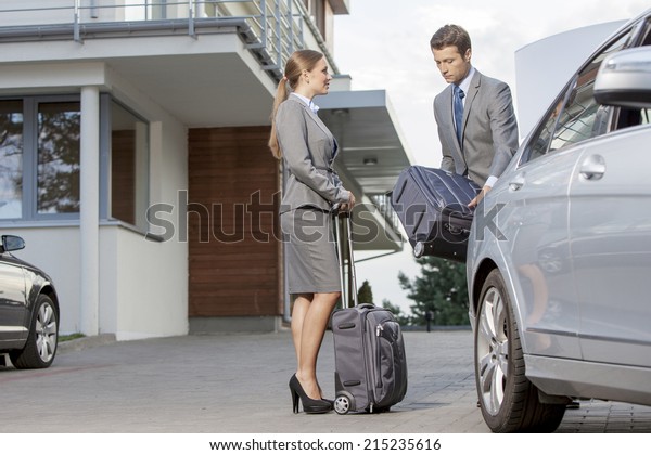 Businesspeople\
unloading luggage from car outside\
hotel