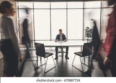 businesspeople walking in office, one man look at camera, pronounced motion blur