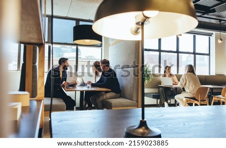 Businesspeople working in a modern co-working space. Diverse business professionals having discussions while sitting in an open workspace. Entrepreneurs collaborating on new projects.