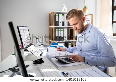 Businessperson Calculating Invoice With Computer On Desk
