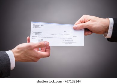 Businessperson Giving Cheque To Colleague On Grey Background