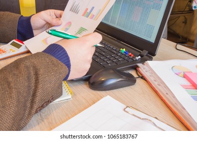 Businesspersons analyzing report, business performance concept. Corporate businessman working at office desk, he is using a calculator and laptop