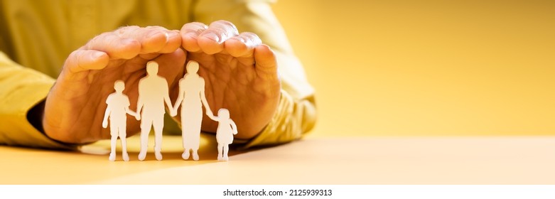 Businessperson's Hand Protecting Family Figure Cut Out