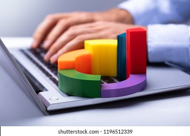 Businessperson's Hand Using Laptop With Colorful 3d Pie Chart On Keypad - Powered by Shutterstock