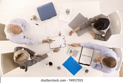 Businessteam Busy Working At Meeting Table, Pointing At Document, Overhead View.?