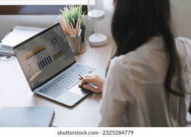 A businesswoman or accountant using laptop to analyze financial investments and business and marketing growth on a data graph. The concepts of accounting, economics, and commercial analysis - Powered by Shutterstock