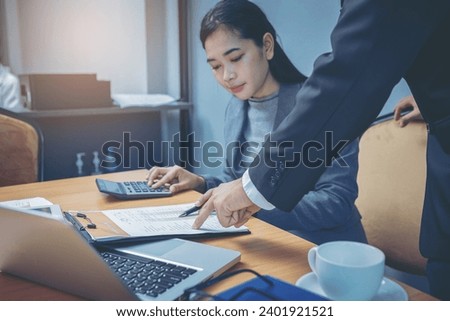 Businesswoman accountant working on desk using calculator for calculate money and checking finance report guided by her colleagues. Selected focus