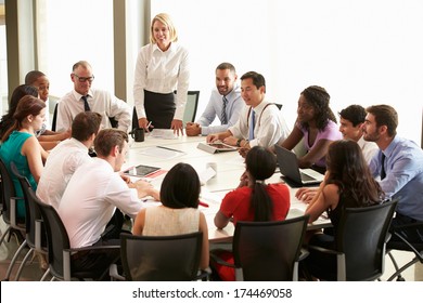 Businesswoman Addressing Meeting Around Boardroom Table