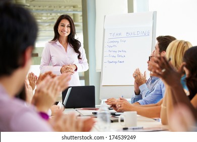 Businesswoman Addressing Meeting Around Boardroom Table