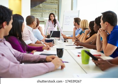 Businesswoman Addressing Meeting Around Boardroom Table