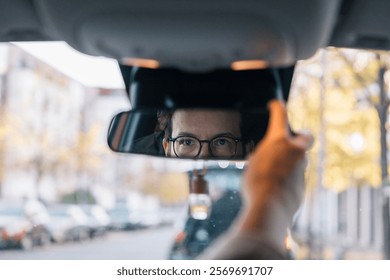 Businesswoman adjusting rearview mirror while driving to work