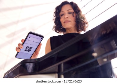 Businesswoman In Airport Departure Lounge Scanning Digital Boarding Pass On Smart Phone