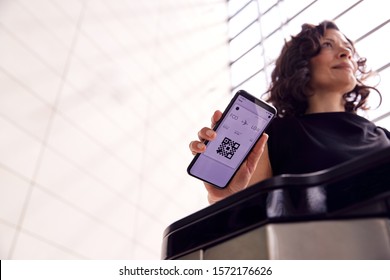 Businesswoman In Airport Departure Lounge Scanning Digital Boarding Pass On Smart Phone