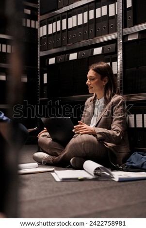 Businesswoman analyzing bookkeeping report, searching files with administrative research in corporate depository. Diverse employees working late at night in arhive room, reading management record