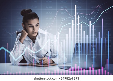 Businesswoman analyzing financial data, writing on a notepad in front of a laptop. Financial graphs overlay on office background. Concept of market analytics and strategy - Powered by Shutterstock