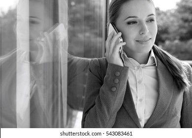 Businesswoman Answering Cell Phone By Glass Door