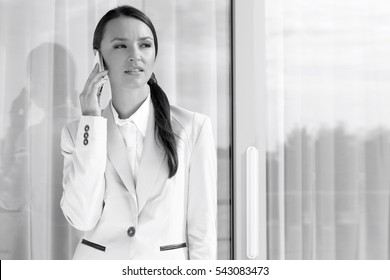 Businesswoman Answering Cell Phone By Glass Door