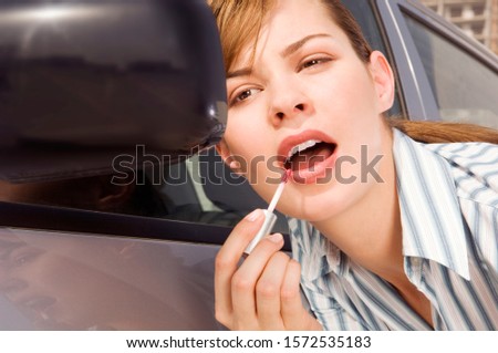 A businesswoman applaying lip gloss