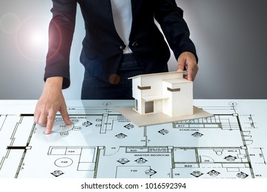 Businesswoman (Architect / Interior Designer) Working With Lay Out Plan & Home Model On Modern Futuristic Virtual Table