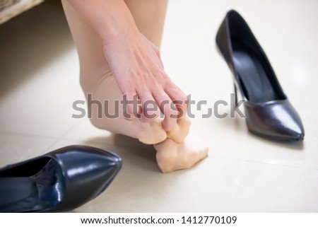 Businesswoman with athlete foot and scratching her foot