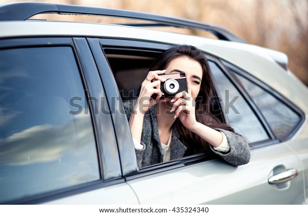 Businesswoman, bank and insurance worker. Tourist\
people concept - beautiful successfull woman make photo on camera\
outside the car. Stylish\
purse.