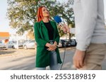 Businesswoman being interviewed by a journalist on a city street, talking and sharing information outdoors with a microphone symbolizing communication