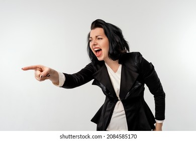 Businesswoman in black formal jacket white shirt pointing to lateral copy space with an angry aggressive expression, looking like a furious, crazy boss, isolate white background. Business concept