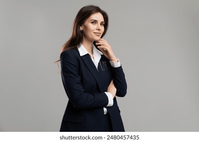 Businesswoman in blazer and dress shirt, hand on chin, pondering at an event - Powered by Shutterstock