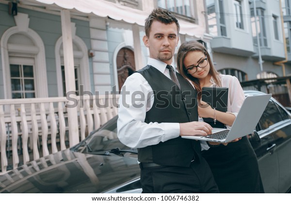 Businesswoman and businessman going over plans before\
getting into a\
car