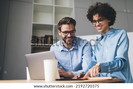 Businesswoman and businessman looking something in notebook. Concept of business cooperation and teamwork. Young smiling caucasian millennial people at table in office. Modern successful people