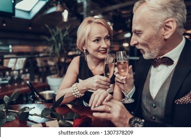 Businesswoman And Businessman . Old Business People .Successful Old People. Relax Together. Romantic Meeting, Rich People. Couple Resting In Restaurant. Look At Each Other. Holding Champagne Glasses