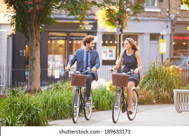 Businesswoman And Businessman Riding Bike Through City Park