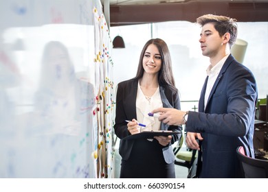 Businesswoman and businessman standing in front of white board and planning new business in the office.