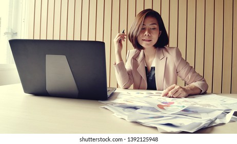 Businesswoman busy with job at office desk working with laptop computer overwhelmed by paperwork workload covering her face.