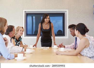 Businesswoman By Screen Addressing Boardroom Meeting